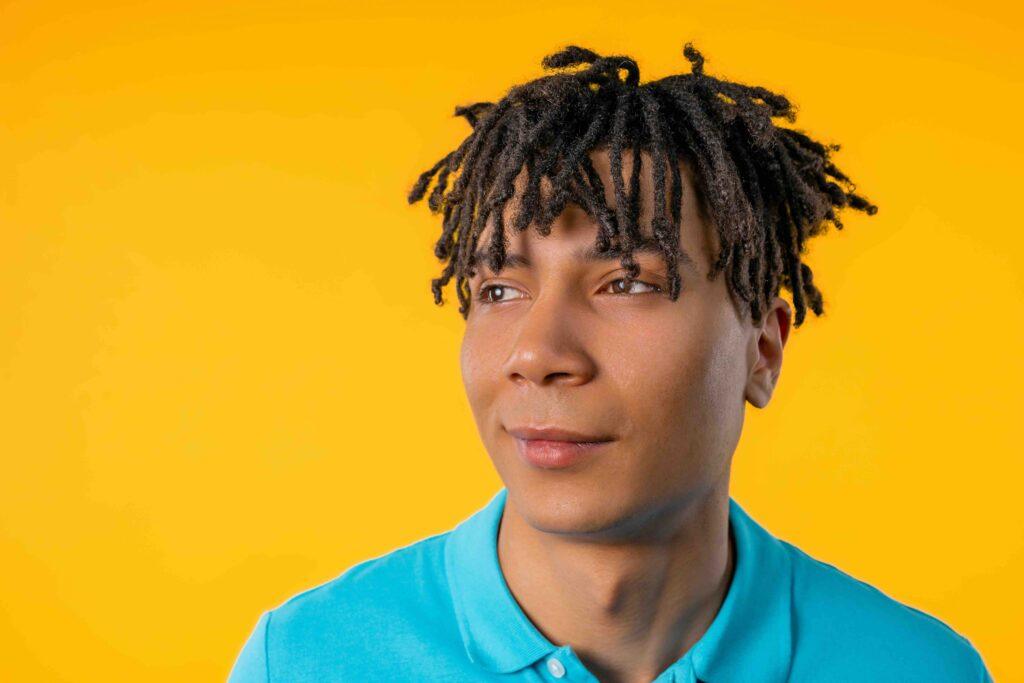 Jeune homme sympathique sur fond de studio jaune. Espace de copie. Étudiant adolescent