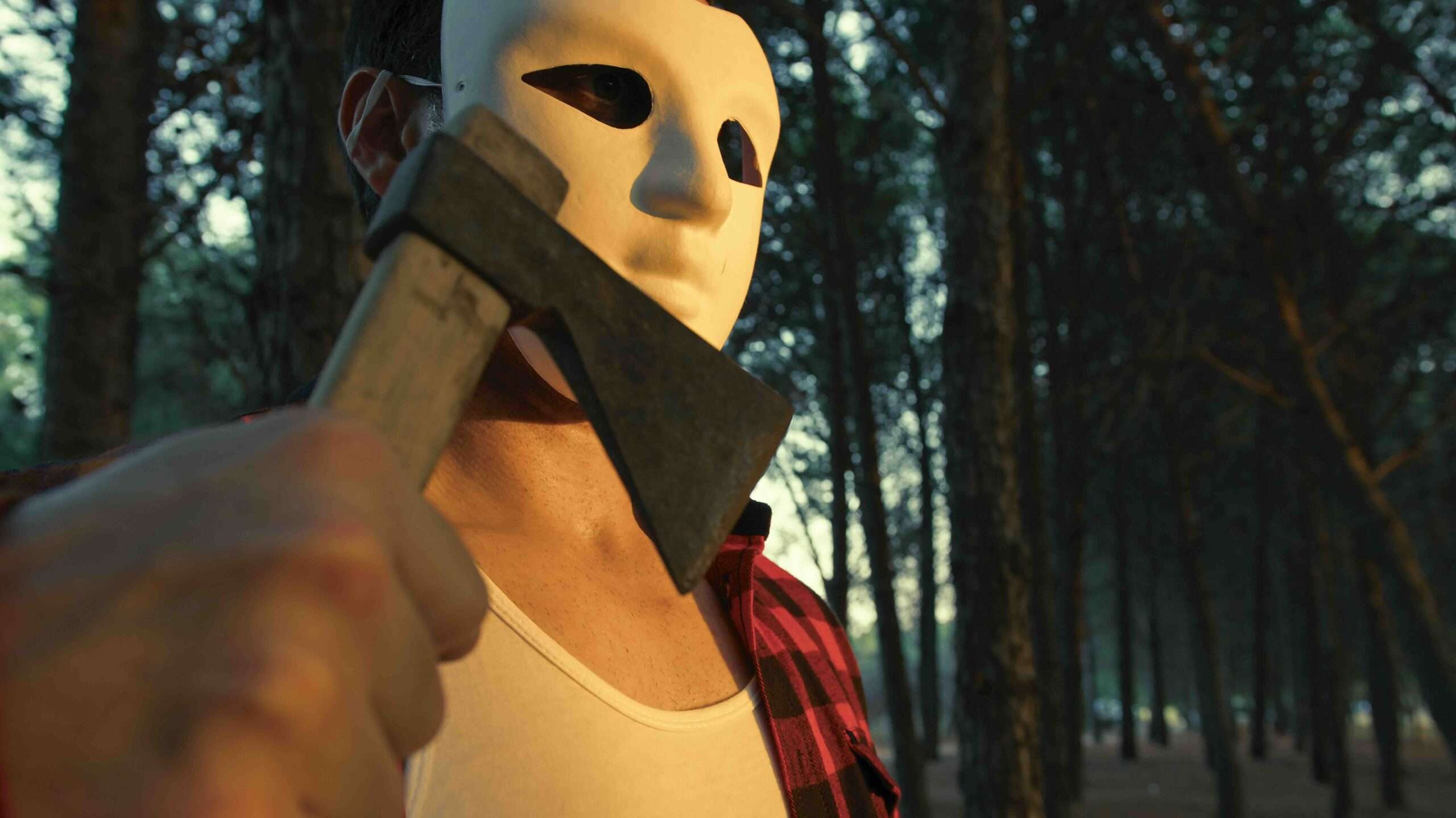 Un assassin masqué avec une hache marche dans la forêt des montagnes